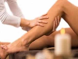 Therapist performing traditional Thai leg massage on a clients lower body.