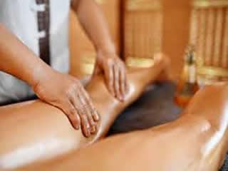 Therapist performing traditional Thai leg massage on a client lying down.